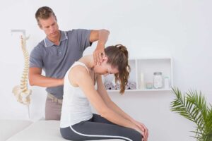 A chiropractor discusses treatment plans with a patient in a comfortable, sunlit clinical office.