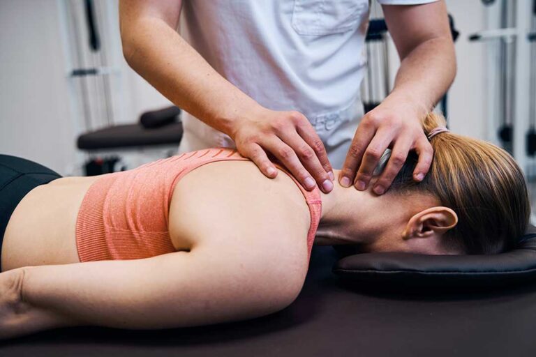 Athlete receiving a careful spinal adjustment beside a treatment table with exercise bands nearby.