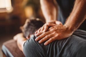 Chiropractor reviewing a patient’s health history before a movement examination in a bright clinic room.